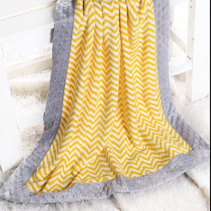 a yellow and gray blanket sitting on top of a white chair