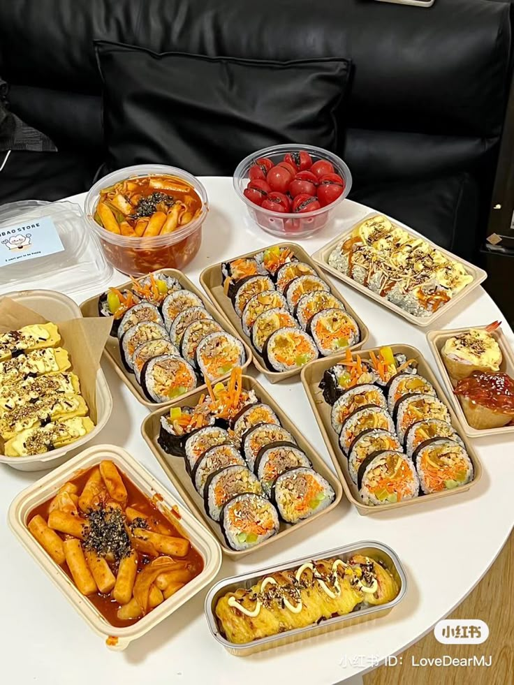 a table topped with lots of trays of food next to a black leather couch