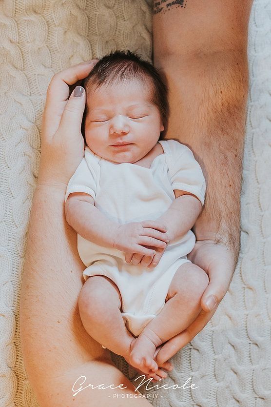 a man holding a baby in his arms on top of a white blanket with tattoos