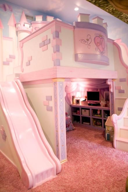 a pink princess castle bed and slide in a room with carpeted flooring on the walls