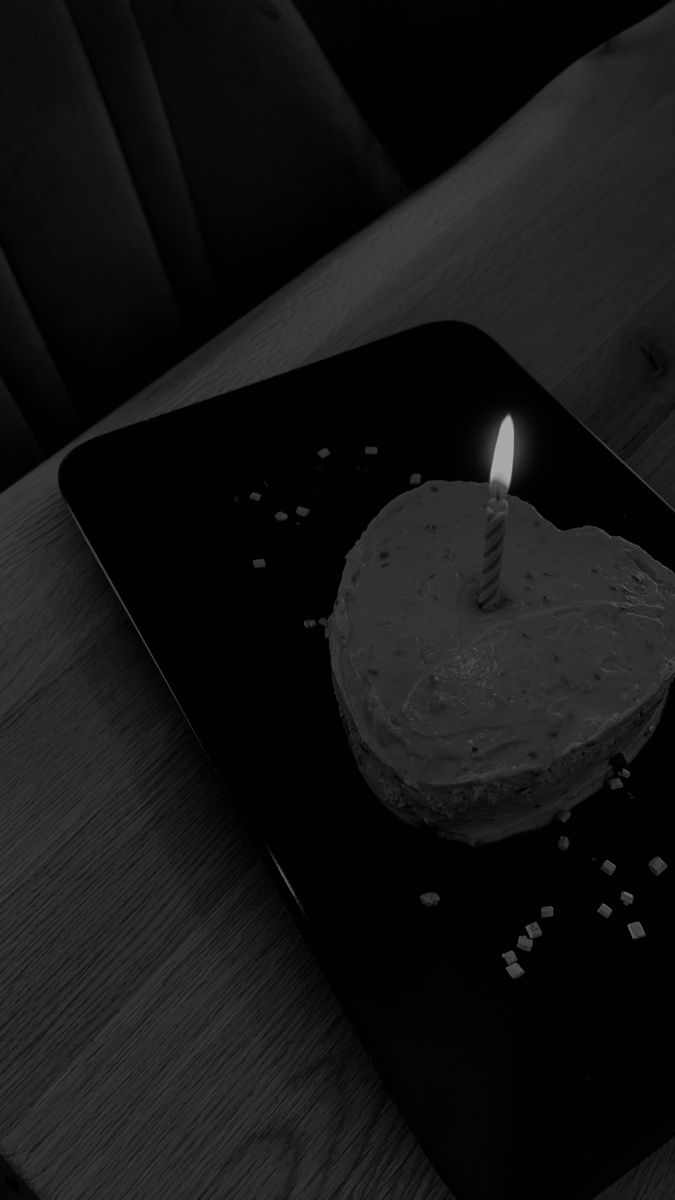 a small white cake with a single candle on it sitting on a black platter