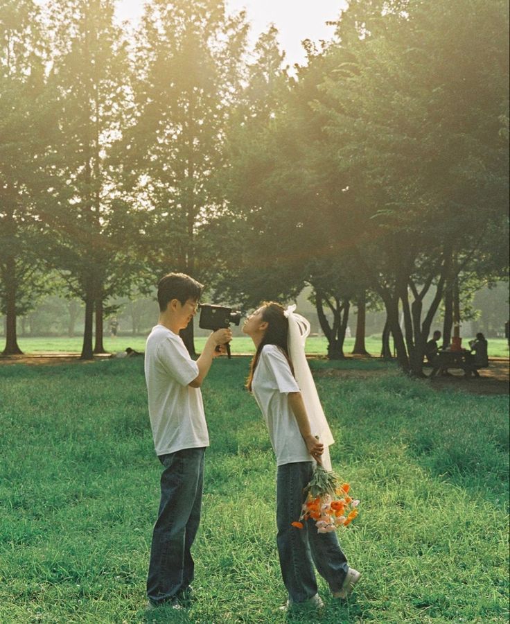 two people are standing in the grass taking pictures