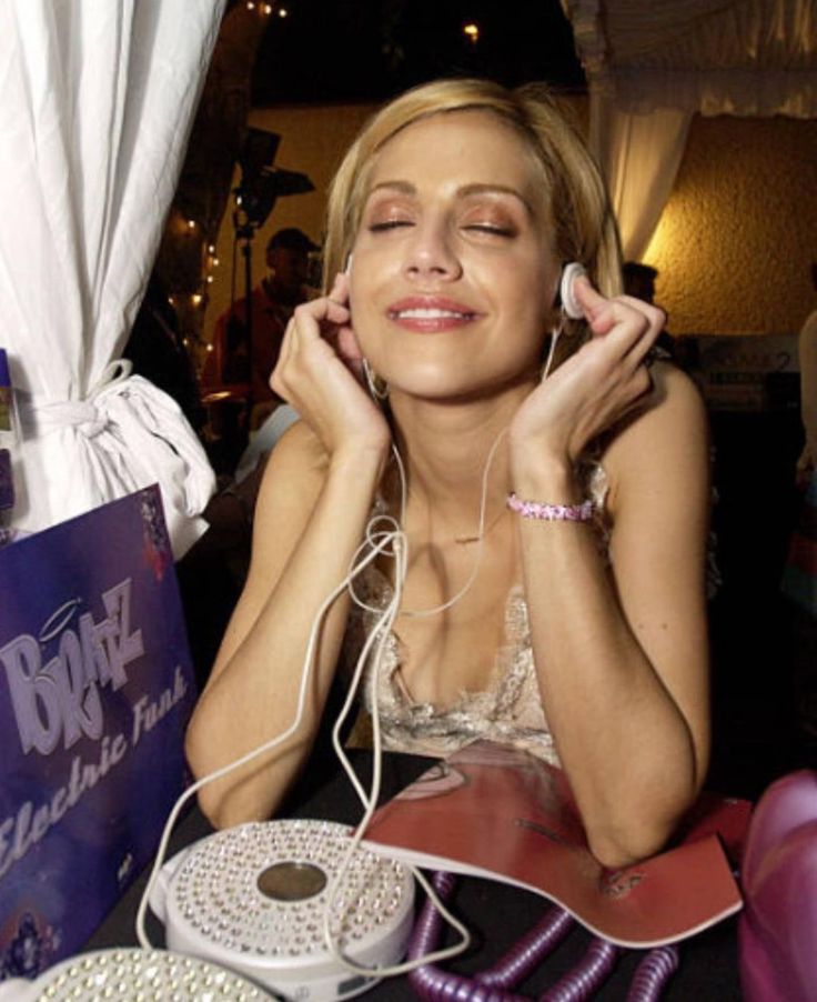 a woman sitting at a table with headphones on her ears, listening to music