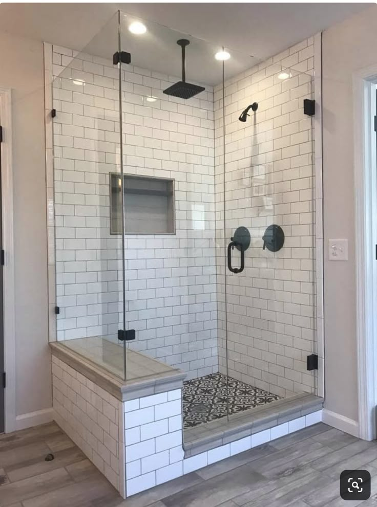 a walk in shower sitting inside of a bathroom next to a door and flooring