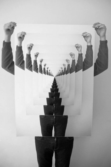 a black and white photo of people holding up their hands in the shape of a triangle