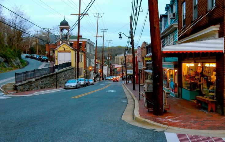 an empty street with cars parked on the side and buildings in the background at dusk