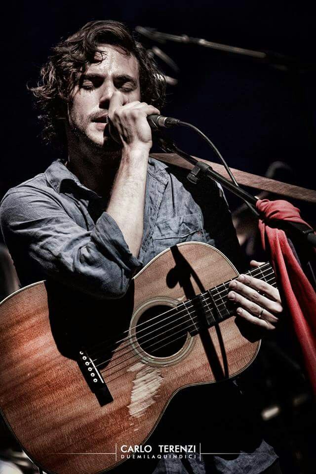 a man holding a guitar while singing into a microphone