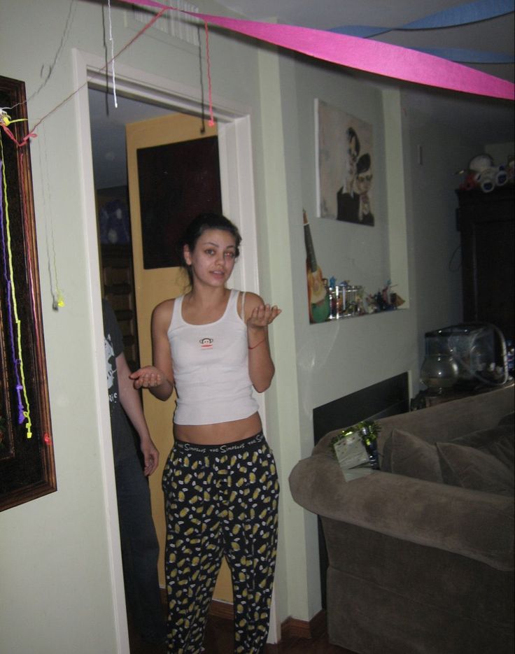 a woman standing in a living room next to a door and looking at the camera