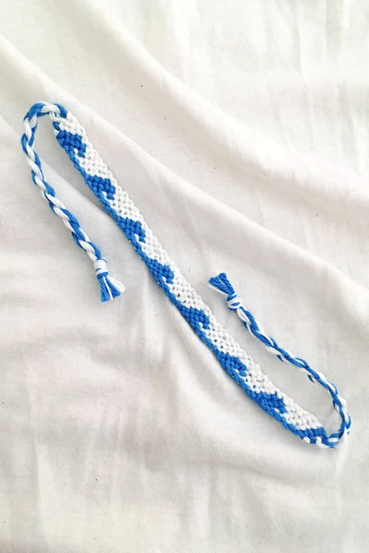 a blue and white rope laying on top of a white bed sheet with two knoted ends