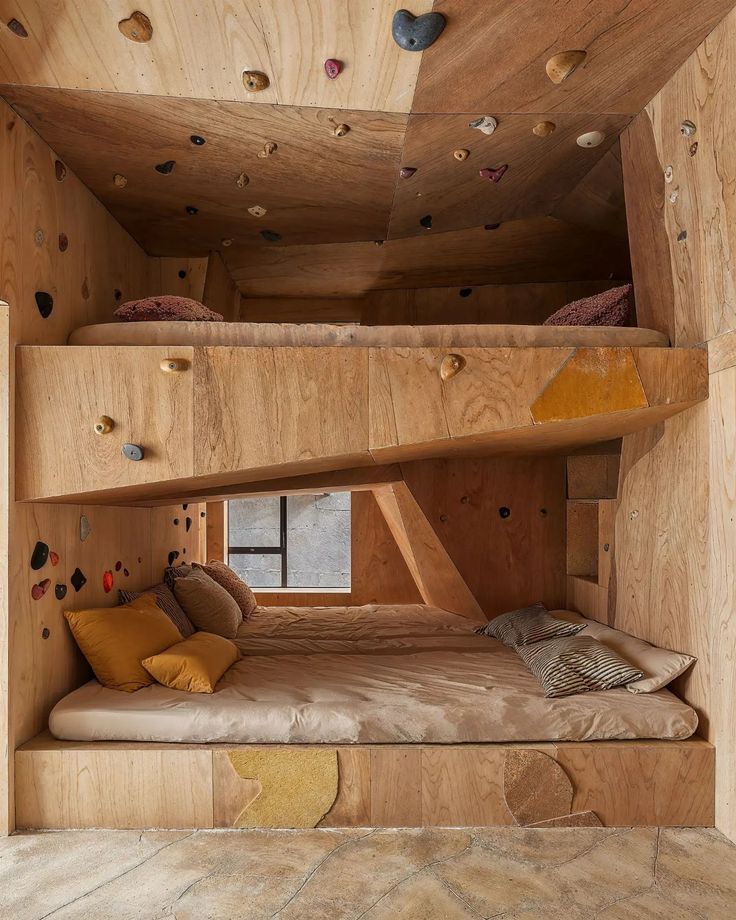 a bunk bed is built into the side of a wooden structure with climbing walls on both sides