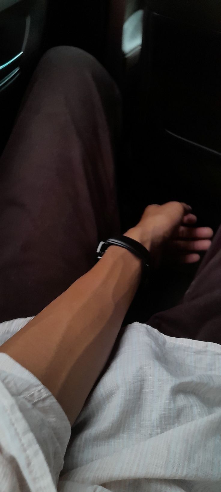 a person laying in bed with their arm wrapped around the edge of his body and wearing a watch