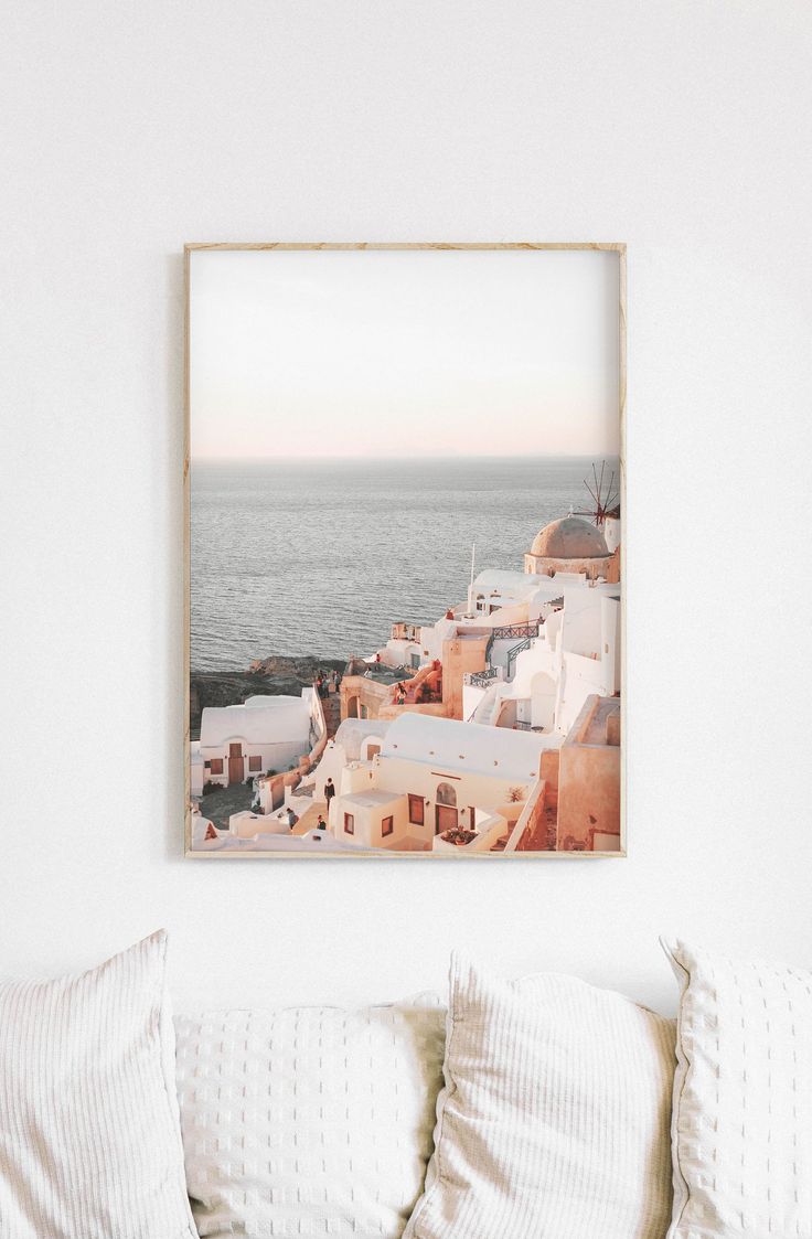 a photo hanging on the wall above a bed in a room with white walls and pillows