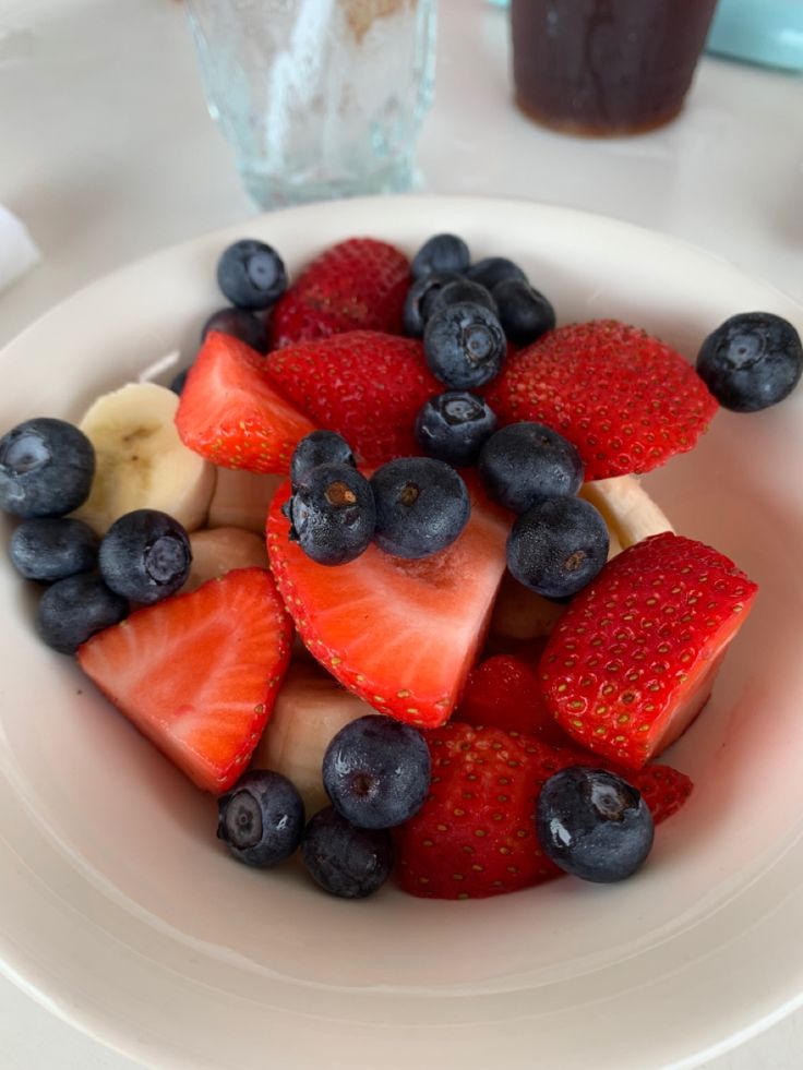 a white plate topped with sliced strawberries and bananas