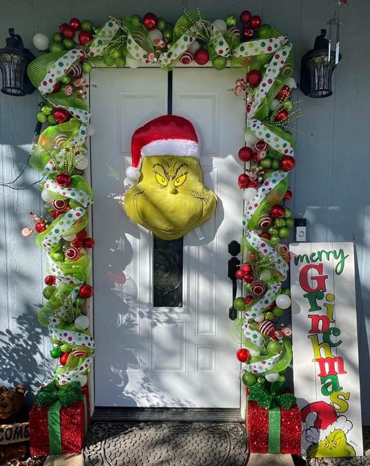 the grin face door decoration is on display in front of a white door with green and red decorations