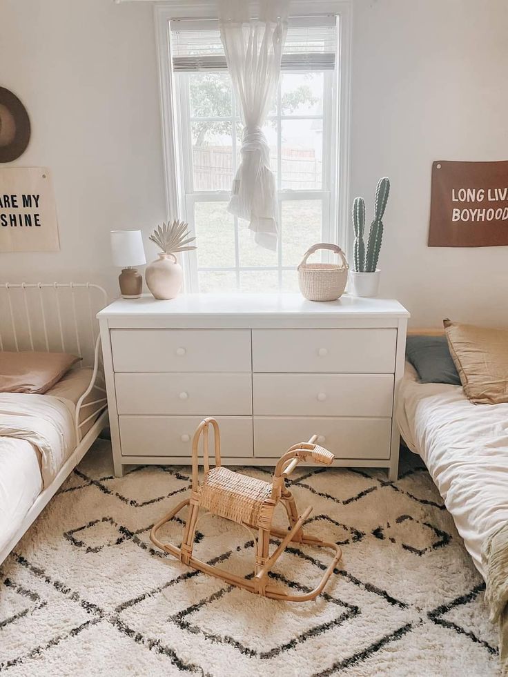 a bedroom with two twin beds and a rocking horse in the foreground is a window