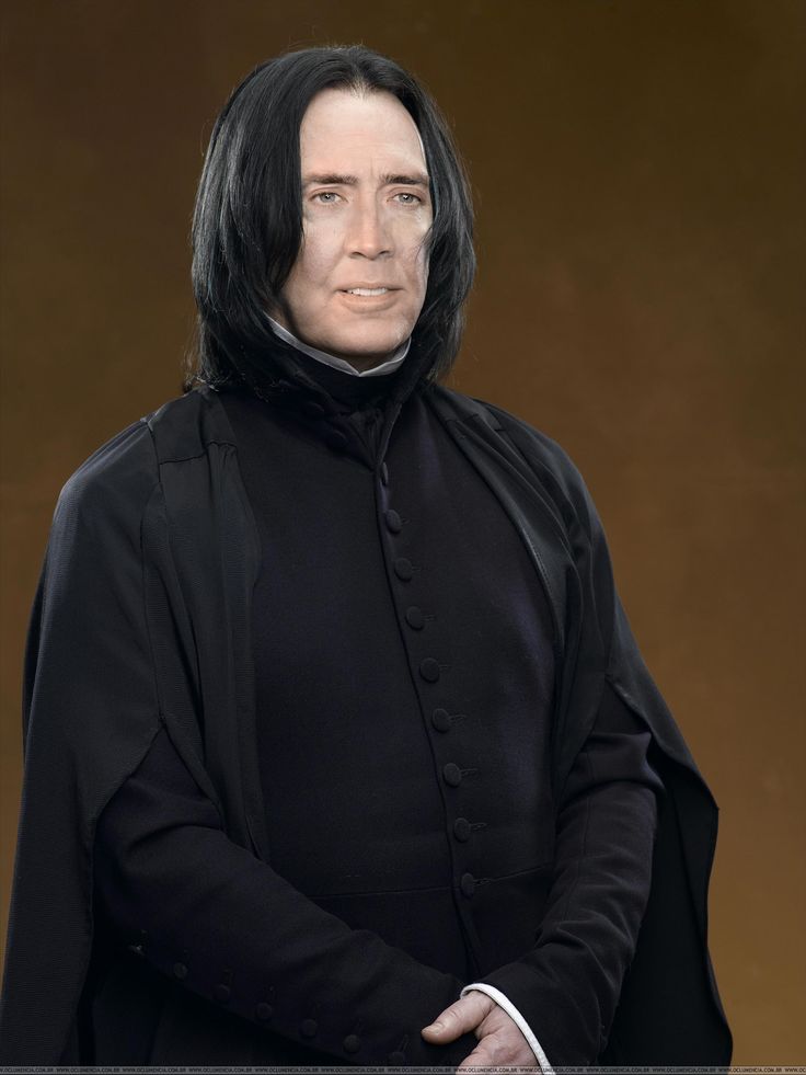 a man with long black hair wearing a black coat and standing in front of a brown background