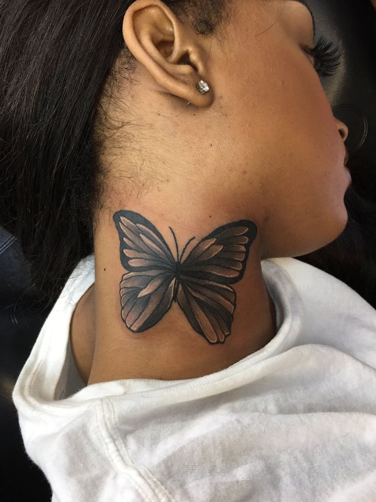 a woman's neck with a butterfly tattoo on the top of her left ear