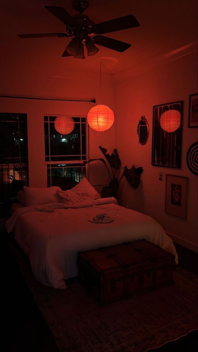 a bed in a room with red light coming from the ceiling and lights hanging on the wall