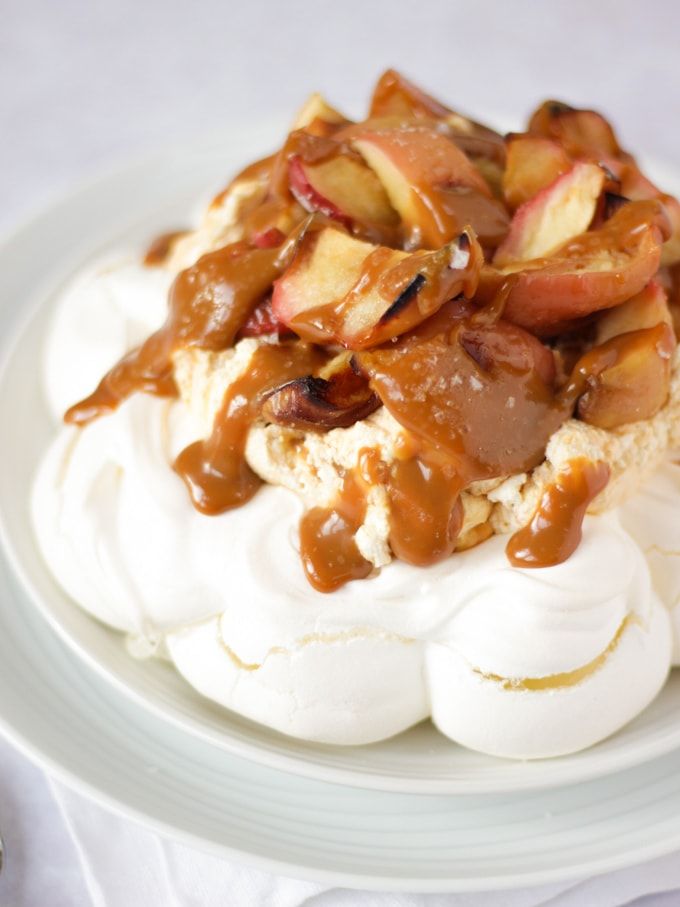 a white plate topped with whipped cream and fruit covered in caramel sauce on top of it