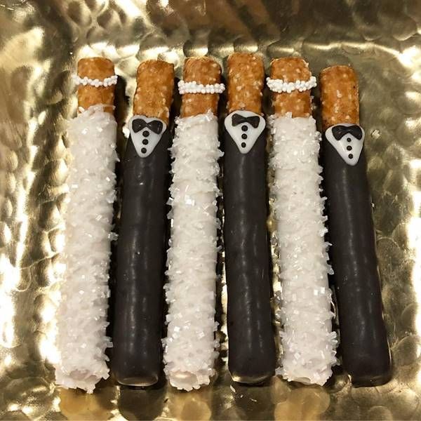 four black and white candy sticks decorated like bride and groom's faces with rice on them