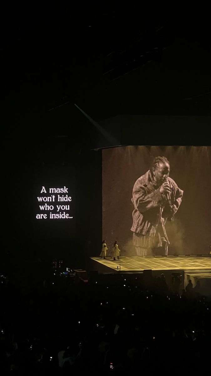 a man standing on top of a stage in front of a screen with words written on it