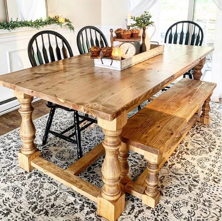 a dining room table with chairs and a bench in front of it on a rug