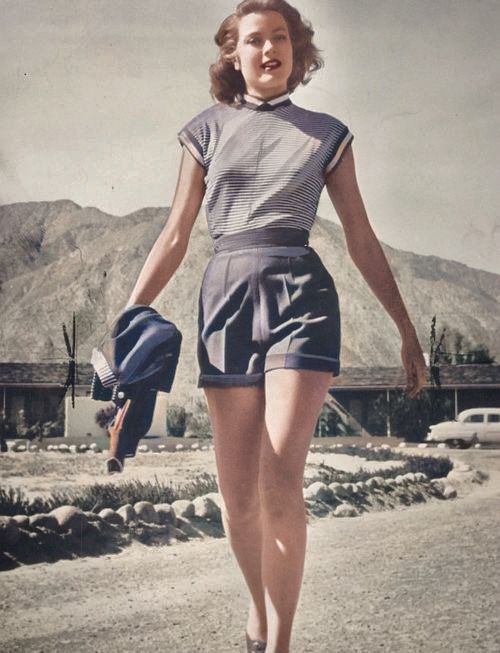 a woman walking down a dirt road in shorts