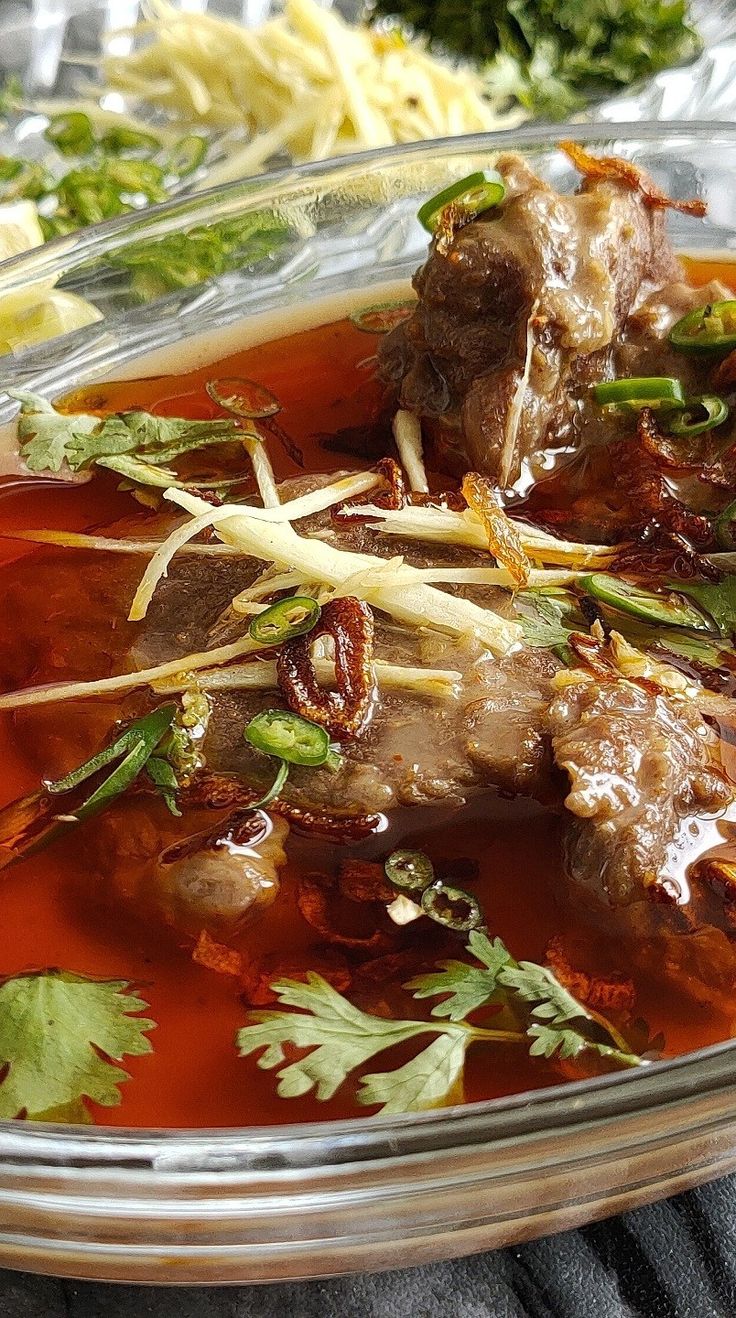 a glass bowl filled with meat and vegetables