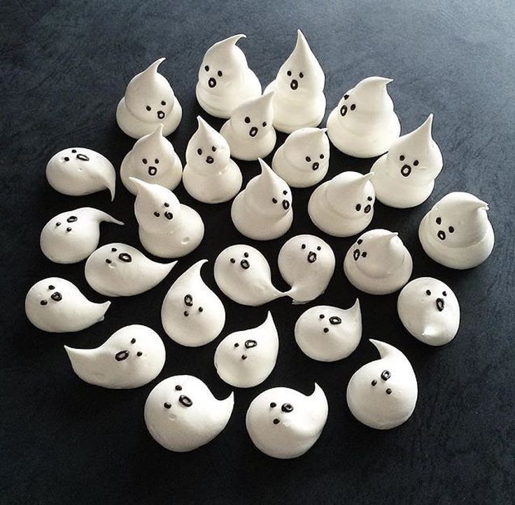 a group of white ghost figurines sitting on top of a black table next to each other