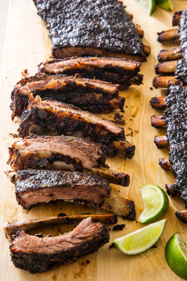 sliced up meat on a cutting board with limes