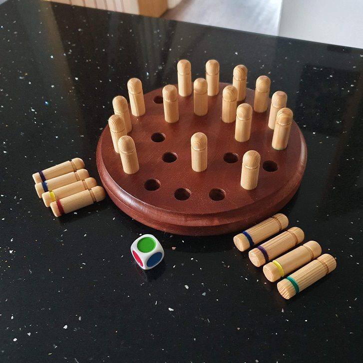 an assortment of wooden pegs on a black counter top next to a game board