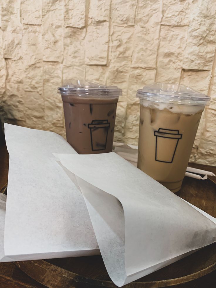 three cups of coffee sitting next to each other on a table with paper napkins