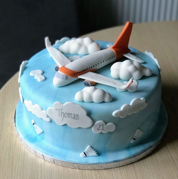 a blue cake with an airplane and clouds on it