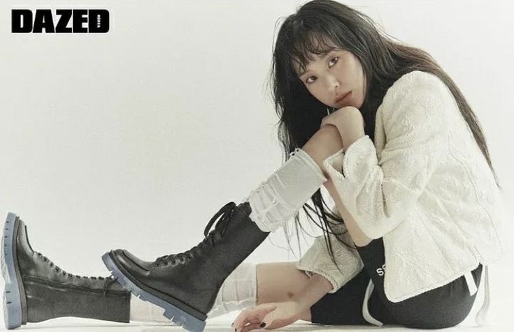 a woman is sitting on the floor with her legs crossed and wearing black combat boots