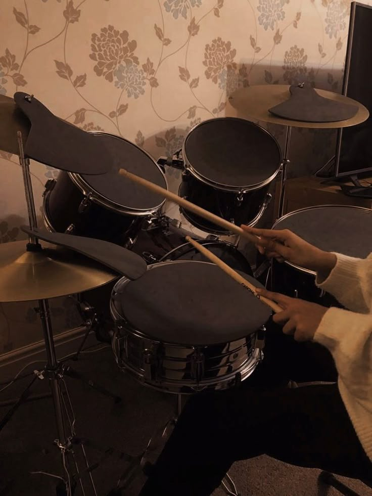 a person sitting in front of a drum set with two sticks sticking out of it