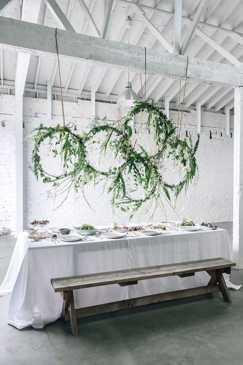 the table is set up with white linens and greenery hanging from the ceiling