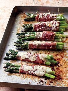 asparagus wrapped in prosciutto and sauce on a baking sheet ready to go into the oven