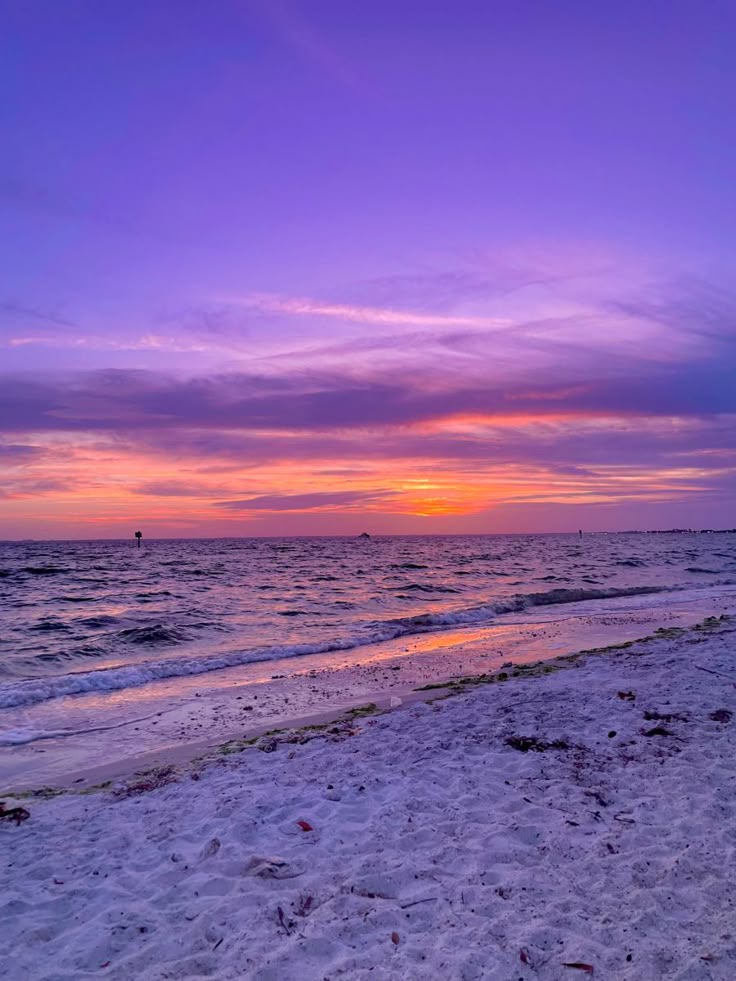 the sun is setting over the ocean on the beach