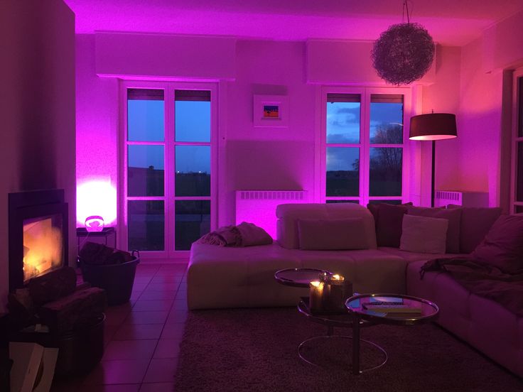 the living room is lit up with purple lighting and candles in front of the windows