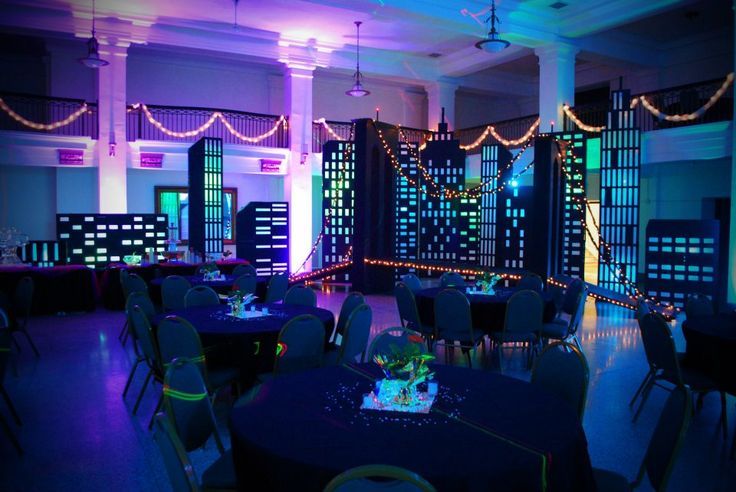 a room filled with tables and chairs covered in blue cloths, decorated with lights