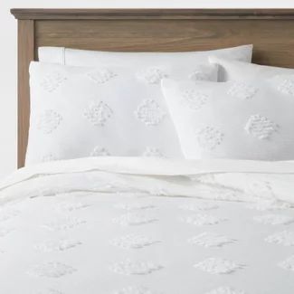 a bed with white sheets and pillows on top of it