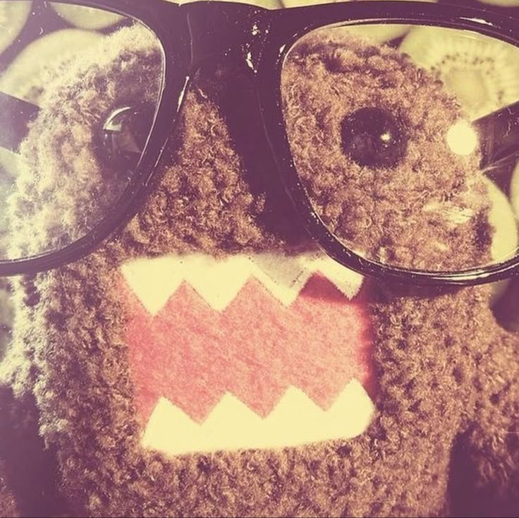 a brown teddy bear wearing glasses on top of a bed