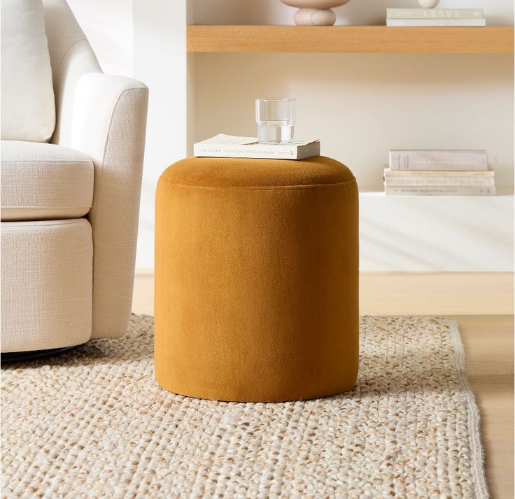 a living room with a chair, ottoman and books on the shelf next to it