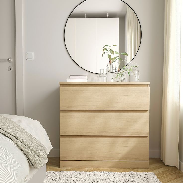 a bedroom scene with focus on the dresser, mirror and plant in the foreground