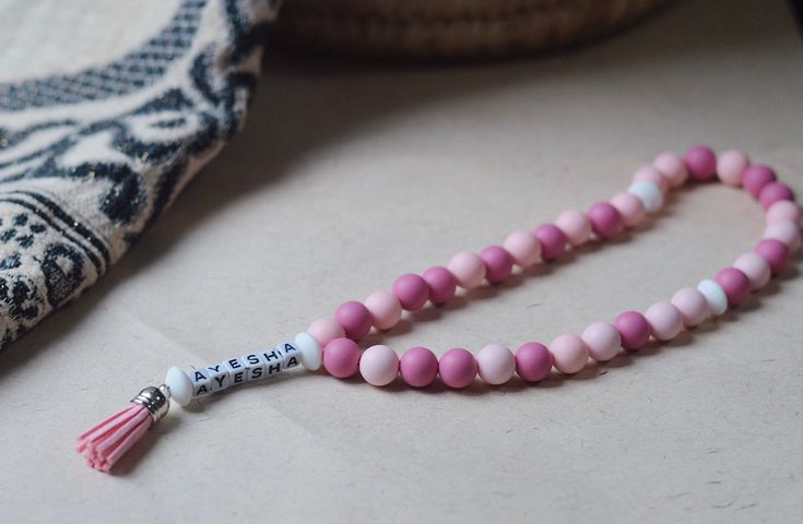 a pink and white beaded necklace with a tassel on it's end