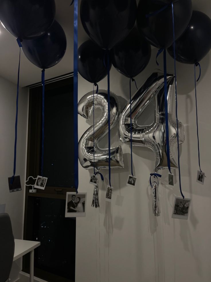 balloons and streamers hang from the ceiling in front of a white room with black walls