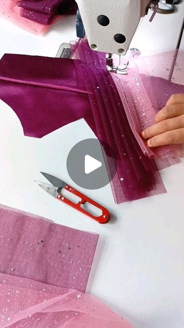 someone using scissors to sew fabric on a sewing machine with pink and purple material