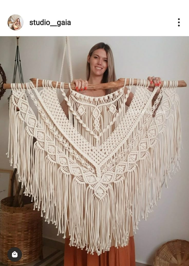 a woman is holding up a white macrame