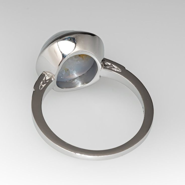 This lovely ring is centered with one (1) round cabochon cut natural star sapphire set into a bezel setting. The shoulders of the ring are each accented with two (2), bead set, round brilliant cut diamonds, bordered with milgrain edging. The ring measures 13.5mm at the top, rises 8.8mm above the finger, tapering to 1.4mm wide and 1.5mm thick at the base of the shank. It is currently a size 7.5. This gorgeous star sapphire has a natural inclusion near the edge but this is very difficult to see wh Classic Oval Cabochon Sapphire Ring With Bezel Setting, Classic Sapphire Ring With Oval Cabochon Bezel Setting, Formal Round Gemstone Cabochons, Fine Jewelry White Gold Cabochons For Anniversary, White Gold Fine Jewelry Cabochons For Anniversary, Elegant Sapphire Ring With Bezel Setting And Oval Cabochon, Classic Round Cabochon Gemstones, Modern Formal Opal Ring With Cabochon, Formal Fine Jewelry Domed Cabochons