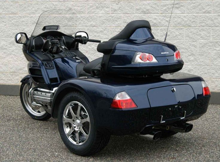 a blue motorcycle parked in front of a building with its back end down and the rear seat up